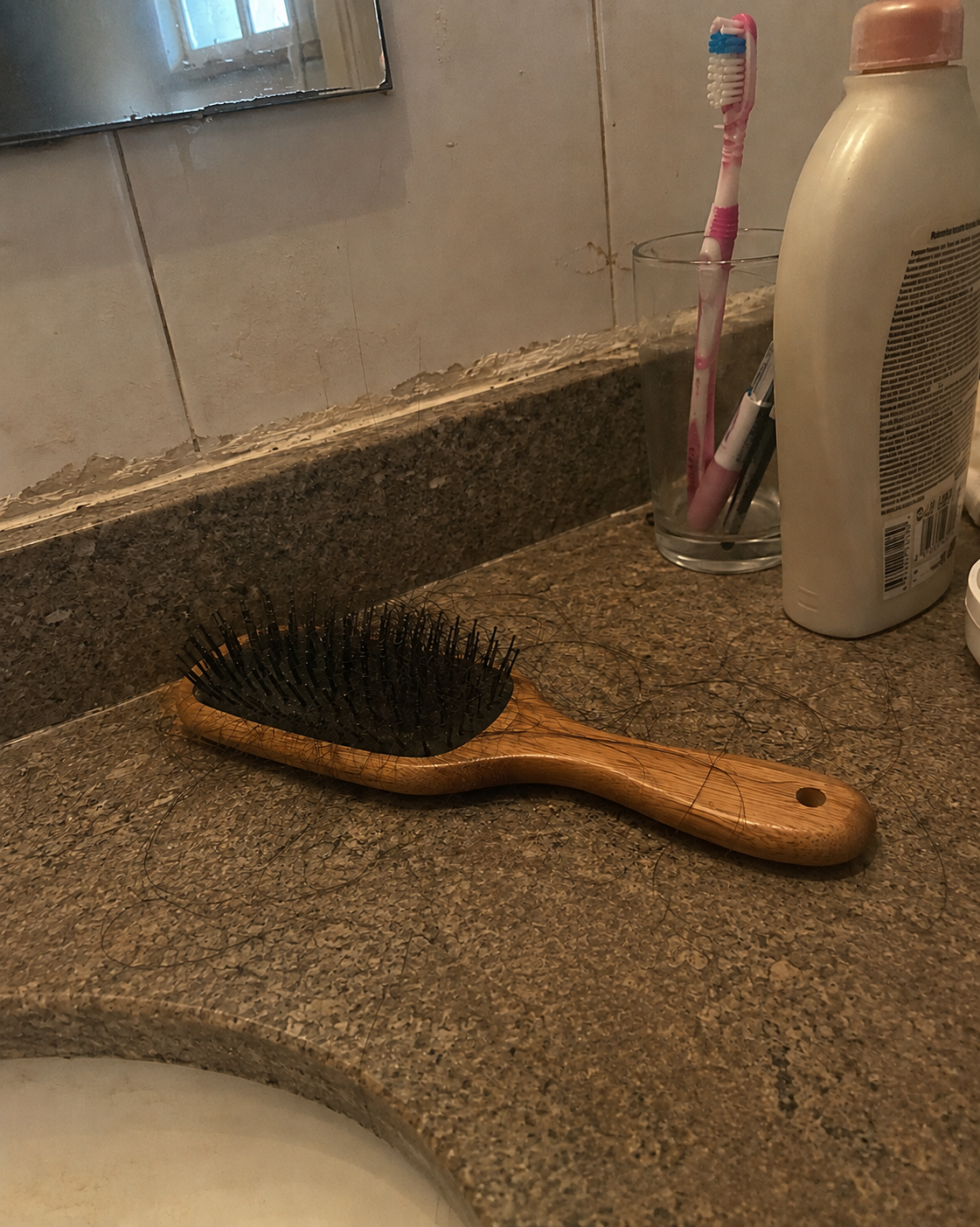 Escova de cabelo e pia com fios caídos, registro feito em casa